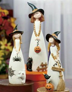 three ceramic figurines with witches and pumpkins on top of a wooden stand