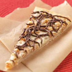 a piece of pizza with nuts and chocolate on top sitting on a paper towel next to a fork