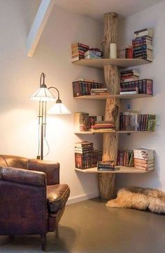 a living room filled with furniture and bookshelves next to a wall mounted lamp