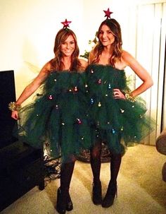 two women dressed in green dresses standing next to each other with christmas decorations on them