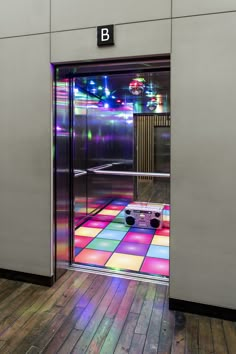 an open door to a brightly lit room with wooden flooring and colorful tiles on the floor