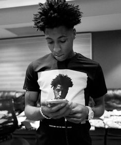 a man looking at his cell phone while wearing a t - shirt with an image of bob marley on it