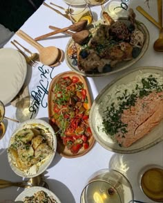 a table topped with lots of different types of food next to wine glasses and utensils