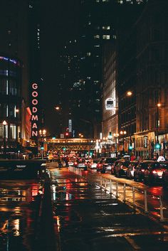 a city street filled with lots of traffic next to tall buildings and lights at night