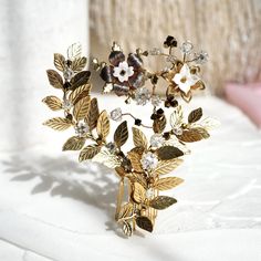 This rustic woodland comb draws inspiration from nature's gentle breeze, with antiquated leaf sprays that curve and sway as if floating in motion.  The delicate design is enhanced by antique gold-plated flower filigrees, handcrafted white blooms, and sparkling Austrian crystals.  Bringing an effortless sense of elegance and natural beauty to any hairstyle, it pairs beautifully with our collection of pins, headbands, and vines for a personalized, cohesive look. Style C116 - Leaffall Comb Materials: - antique gold-plated flowers and leaf sprays - handcrafted clay flowers  - Austrian crystals  - gold-plated comb - gold-plated artistic wire Artfully hand-wired for enduring support, ensuring a timeless and steadfast elegance that stands the test of time with every graceful wear. Each of our pro Autumn Wedding Hair, Autumn Hair Accessories, White Autumn, Fall Wedding Hairstyles, Hair Accessories Pins, Floral Comb, Artistic Wire, Boho Fall, Delicate Design