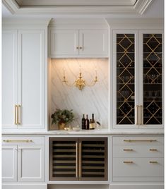 a kitchen with white cabinets and gold accents