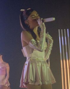 a woman in a white dress singing into a microphone