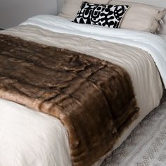 a bed with white sheets and brown fur on it