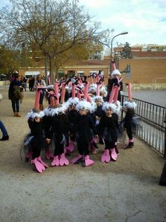 a group of people dressed in costumes standing next to each other on a sidewalk near a fence