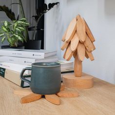 a cup sitting on top of a wooden table next to some books and a plant