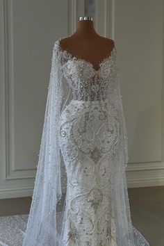 a white wedding dress on display in front of a mannequin headdress