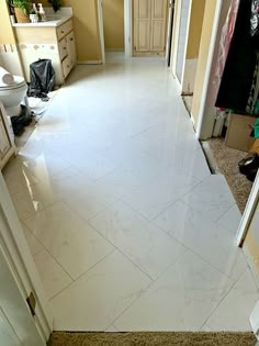 a bathroom with white tile flooring and yellow walls on the other side of the room