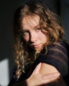 a close up of a person with long hair wearing a black shirt and holding her arms crossed