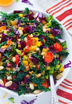 a white bowl filled with salad next to a glass of orange juice