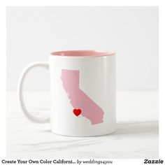 a white and pink coffee mug with a red heart in the shape of california on it