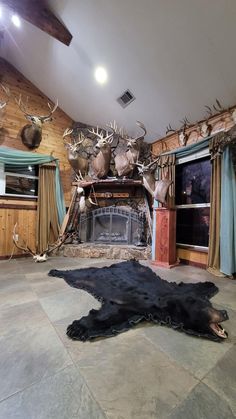 a living room filled with lots of deer heads and antlers on the wall next to a fire place