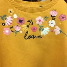 a yellow sweater with flowers and the word love embroidered on it's chestline