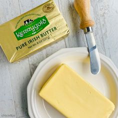 a block of butter sitting on top of a white plate next to a cheese knife