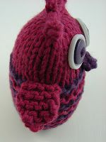 a knitted hat with a button on the side and a cord attached to it