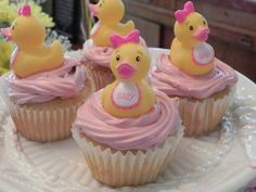 cupcakes decorated with rubber ducks and pink frosting on a white platter