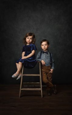 two children are sitting on a stool and posing for the camera