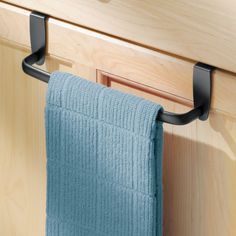 a blue towel hanging on the side of a kitchen cabinet with black metal handles and hooks