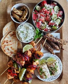 a wooden tray topped with different types of food and veggie skewers