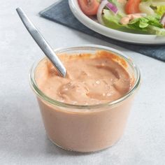 a glass jar filled with chocolate pudding next to a bowl of salad on a table