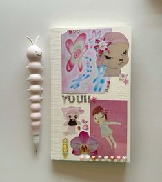 an open notebook with stickers on it next to a small toy and a pen