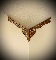 an ornate wooden shelf on the side of a wall with white walls in the background