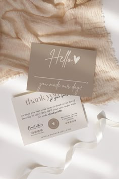 a white and gray wedding thank card on top of a bed with a beige blanket