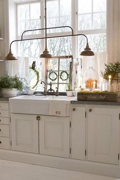 a kitchen sink sitting under a window next to a window sill with lights on it