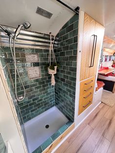 a bathroom with green tiled walls and wooden flooring, including a walk in shower