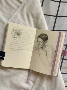 an open notebook with a drawing of a woman's face on the page and writing