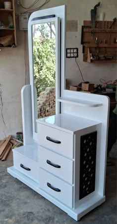 a white dresser with drawers and a mirror on it in a room that is being worked on