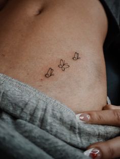 a woman's stomach with three small butterflies on the side, and two smaller ones behind her