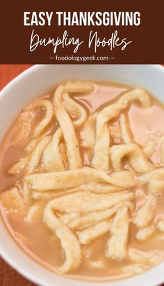 a white bowl filled with noodles and sauce on top of a wooden table next to an orange napkin