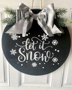 a sign that says let it snow hanging from a door with silver bows on it