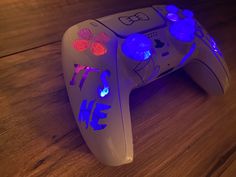 a video game controller sitting on top of a wooden table with blue and red lights