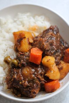 a white bowl filled with rice and meat next to carrots on top of it