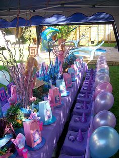 there is a purple table set up with balloons and other items on it for a mermaid themed birthday party