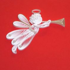 an angel ornament on a red background with a bell in the shape of a trumpet