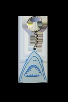 a blue and white keychain with a shark's teeth on the front