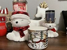 there are many christmas items on the table and one bear is wearing a santa hat