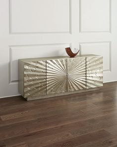 a modern sideboard with an intricate design on the front and sides, against a white wall