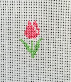 a red flower is embroidered onto a white piece of fabric with green stems on it