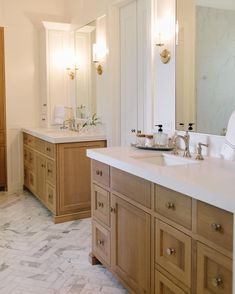 a large bathroom with two sinks and mirrors on the wall, along with marble flooring