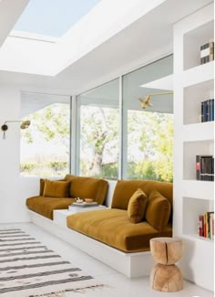 a living room filled with lots of furniture next to large windows and a rug on the floor