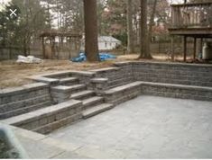 an outdoor patio with steps leading up to the deck and trees in the back yard