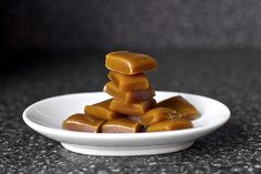 a white plate topped with pieces of caramel on top of a black countertop